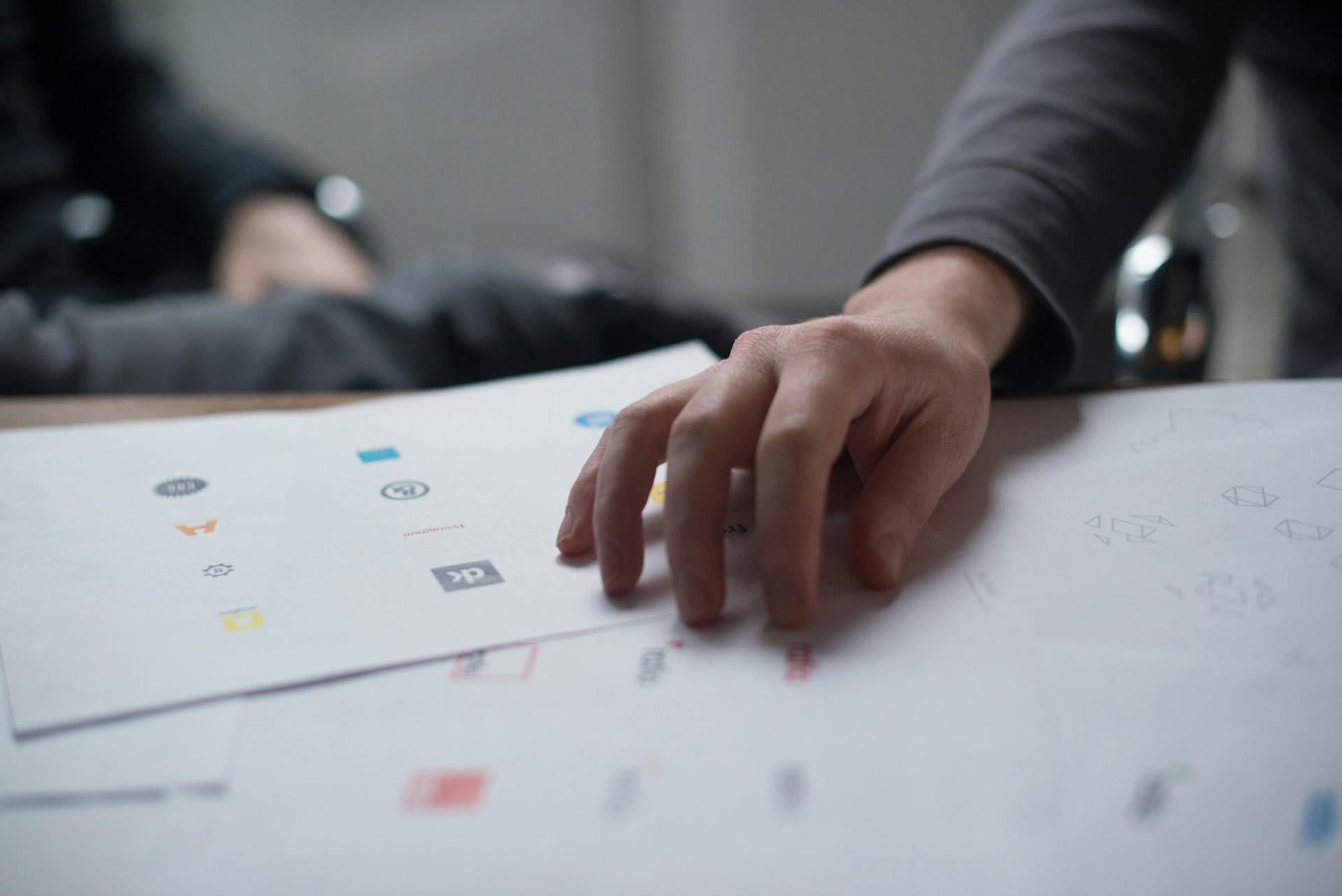 Close-up of a person reviewing printed logo designs on paper, representing Shopify apps, branding, and eCommerce store customization.