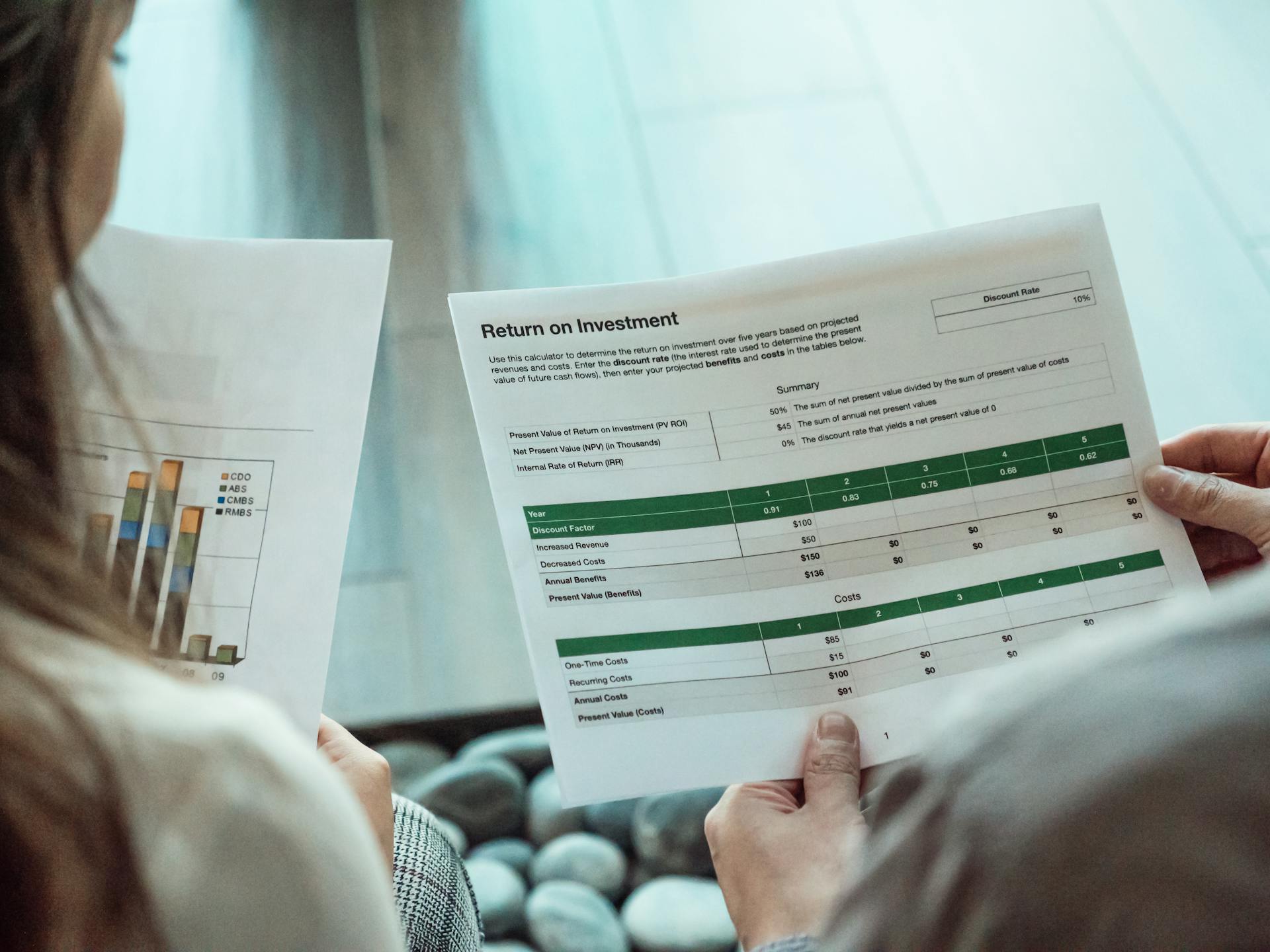 Tracking Pixels That Convert: How to Use Them Effectively 16 Two people reviewing printed reports with charts and ROI tables, symbolizing how tracking pixels help measure conversions, revenue, and marketing return on investment.