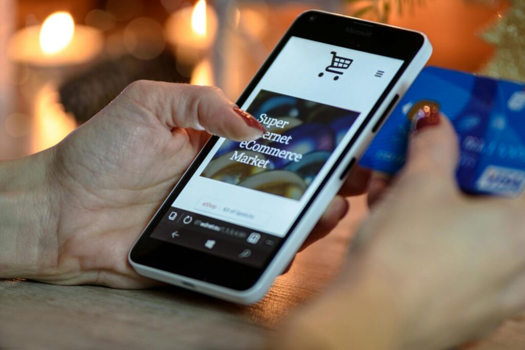 Person shopping on a mobile eCommerce store using a smartphone and credit card, representing Shopify apps, online shopping, and secure checkout optimization.