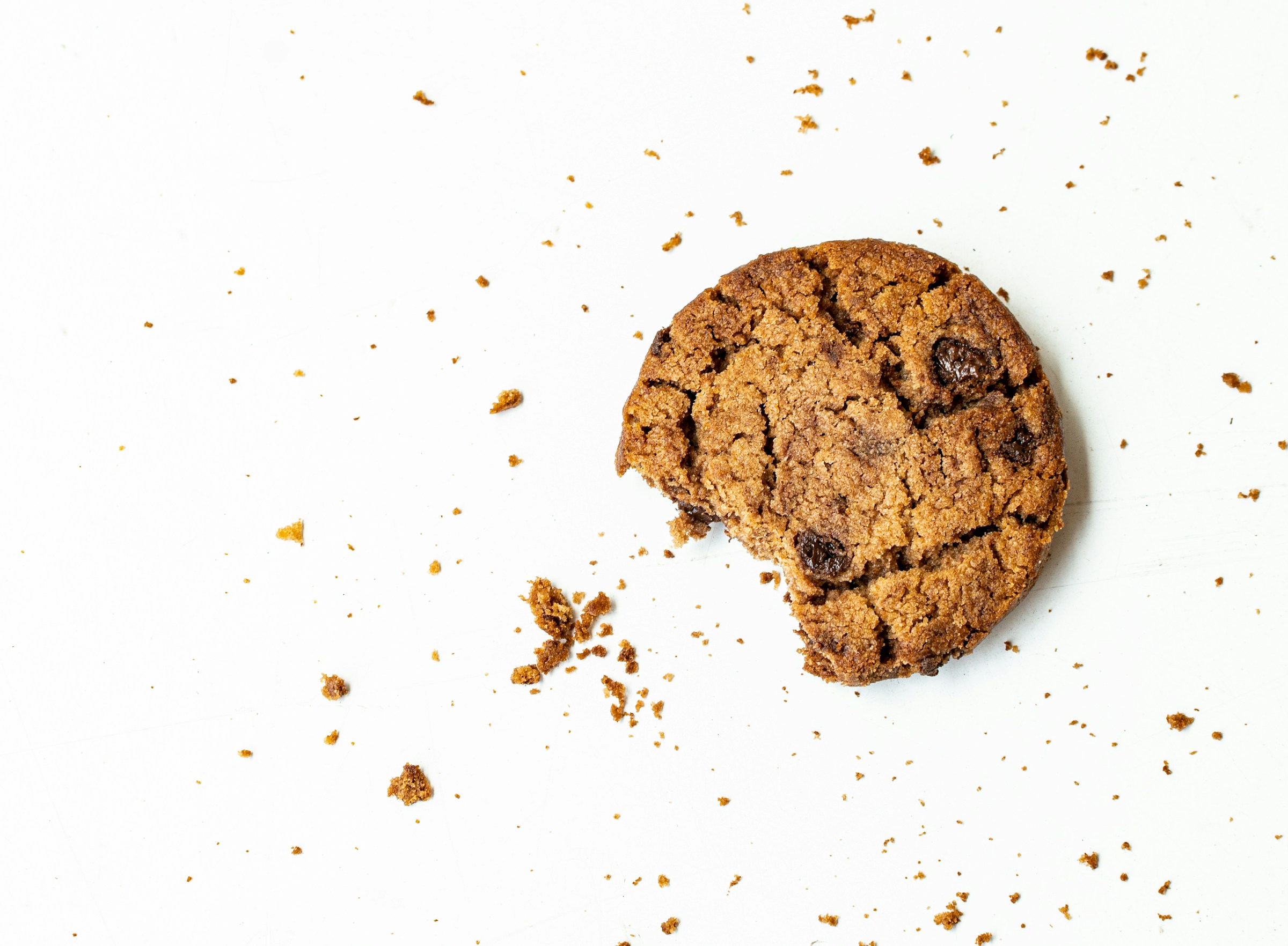 Tracking Pixels That Convert: How to Use Them Effectively 12 Close-up of a bitten chocolate chip cookie with crumbs on a white background, symbolizing cookies and web tracking data.