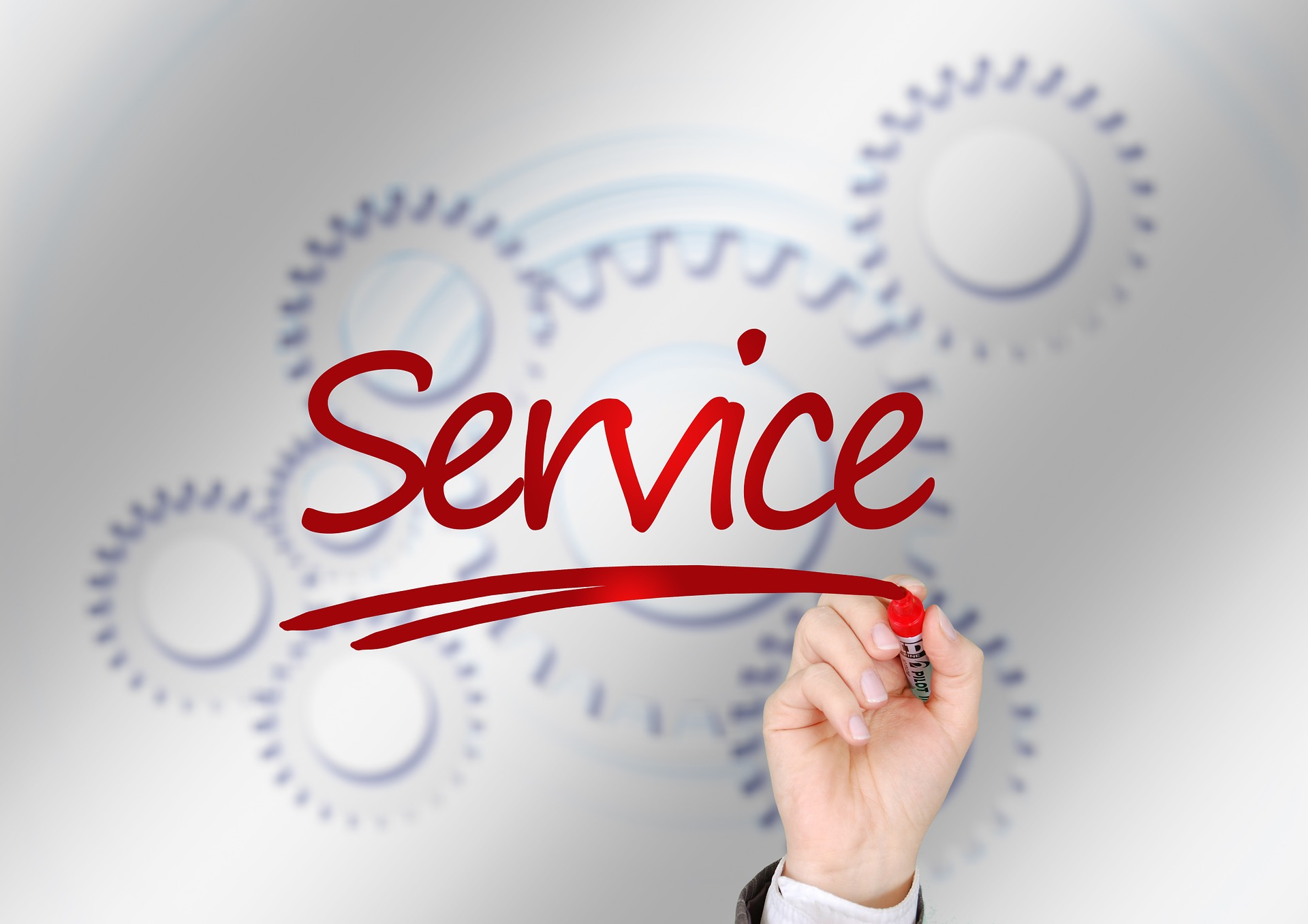 Hand writing the word “Service” with a red marker against a background of gears, symbolizing customer service and its impact on customer reviews and satisfaction.