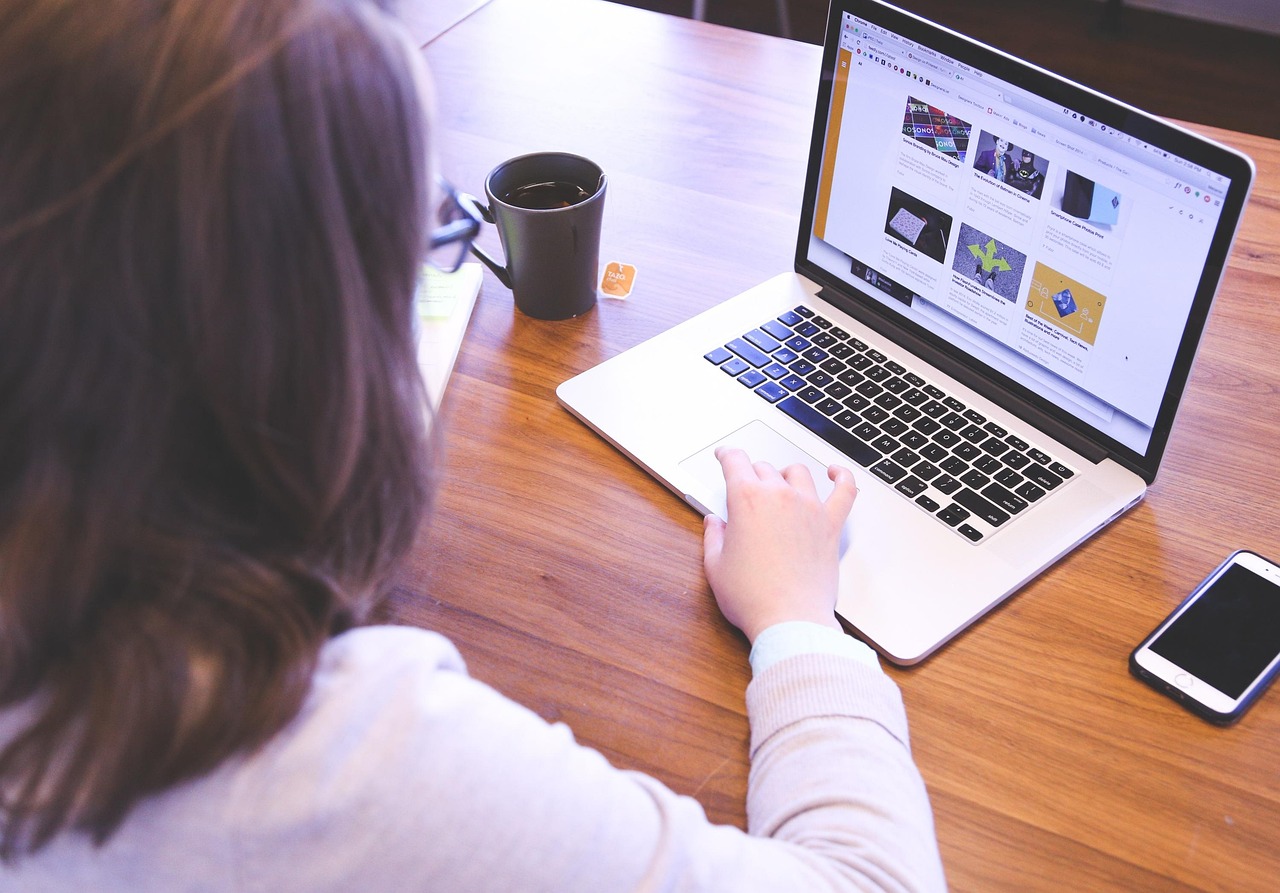 Woman browsing ecommerce website on laptop with coffee cup nearby