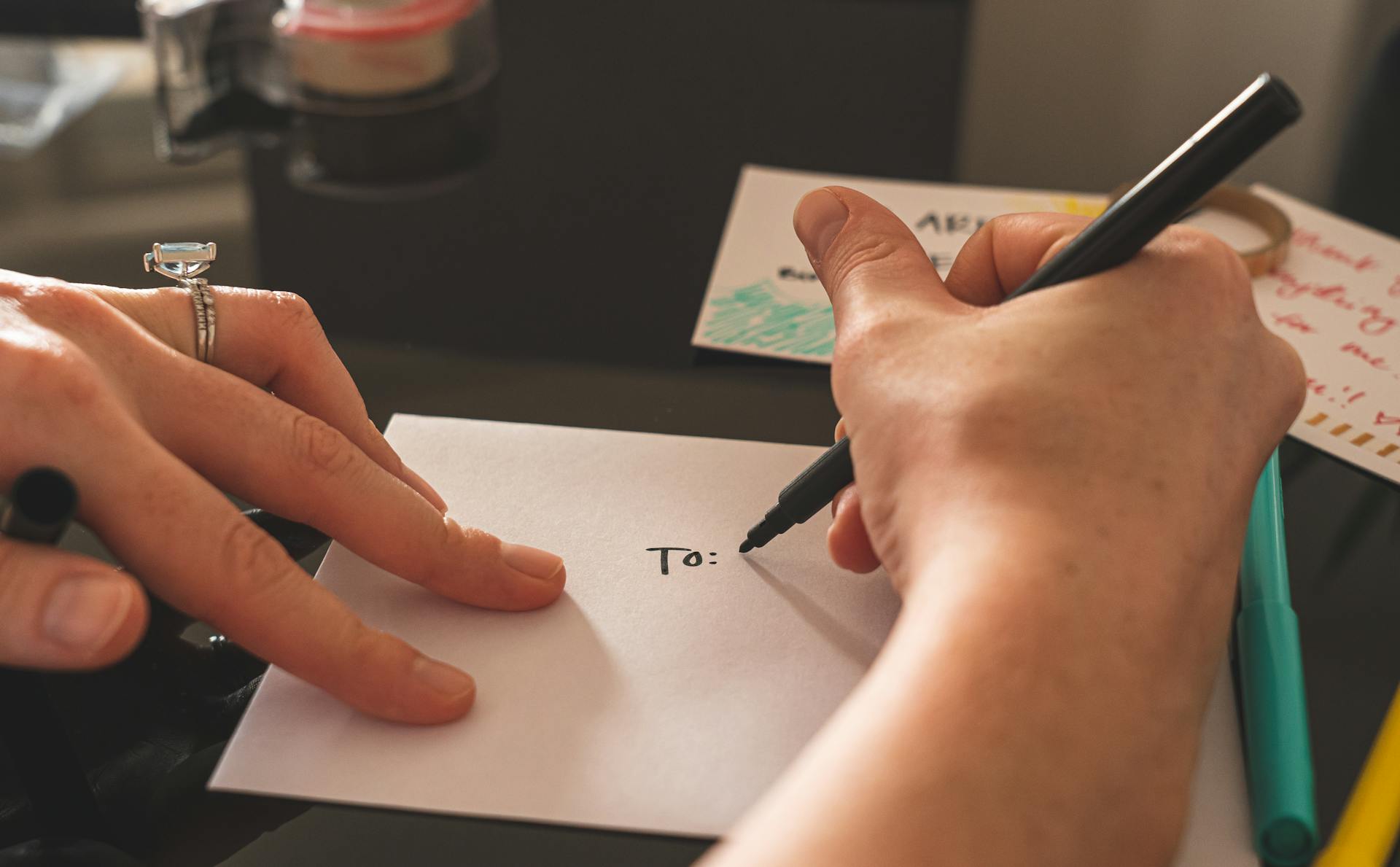 Person addressing an envelope by hand with a black marker, symbolizing personalized email marketing and direct customer communication in ecommerce.