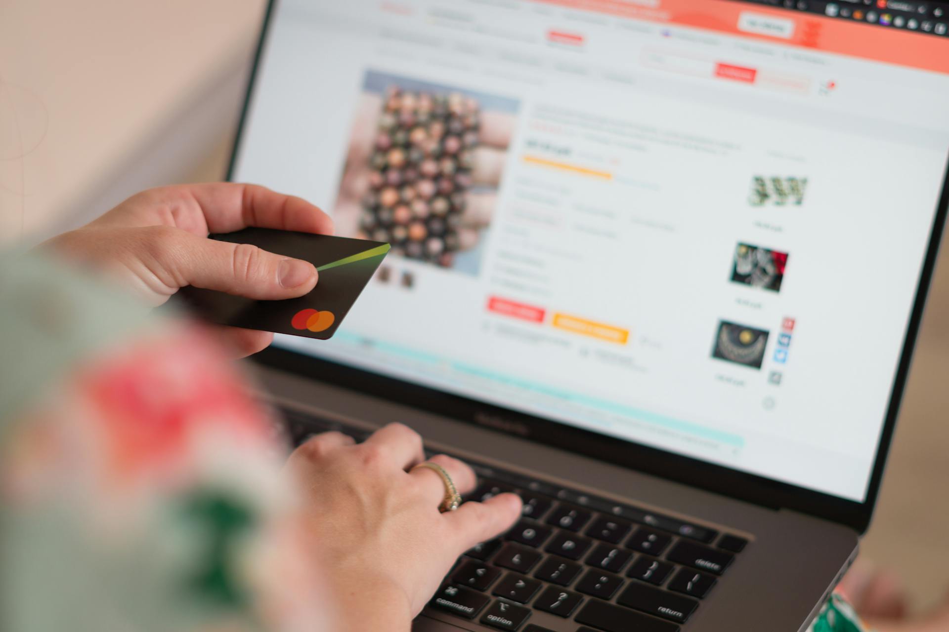 Person holding a credit card while shopping online on a laptop