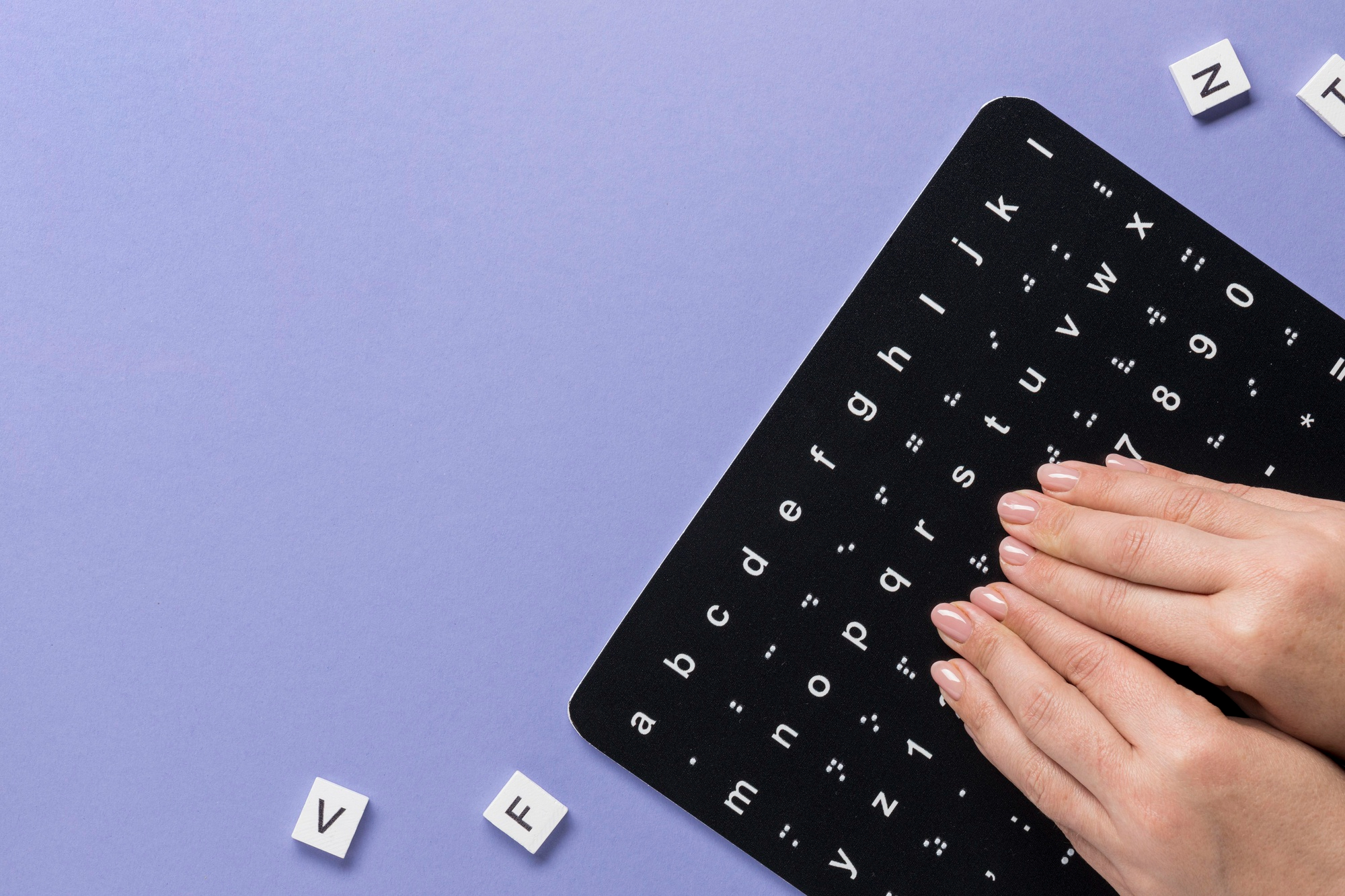 Understanding the Accessibility Act: A Shopify Merchant’s Guide to EAA 2025 12 Hands reading a tactile braille and print alphabet chart on a purple background, representing inclusive design and accessible digital services in compliance with the Accessibility Act (EAA 2025).