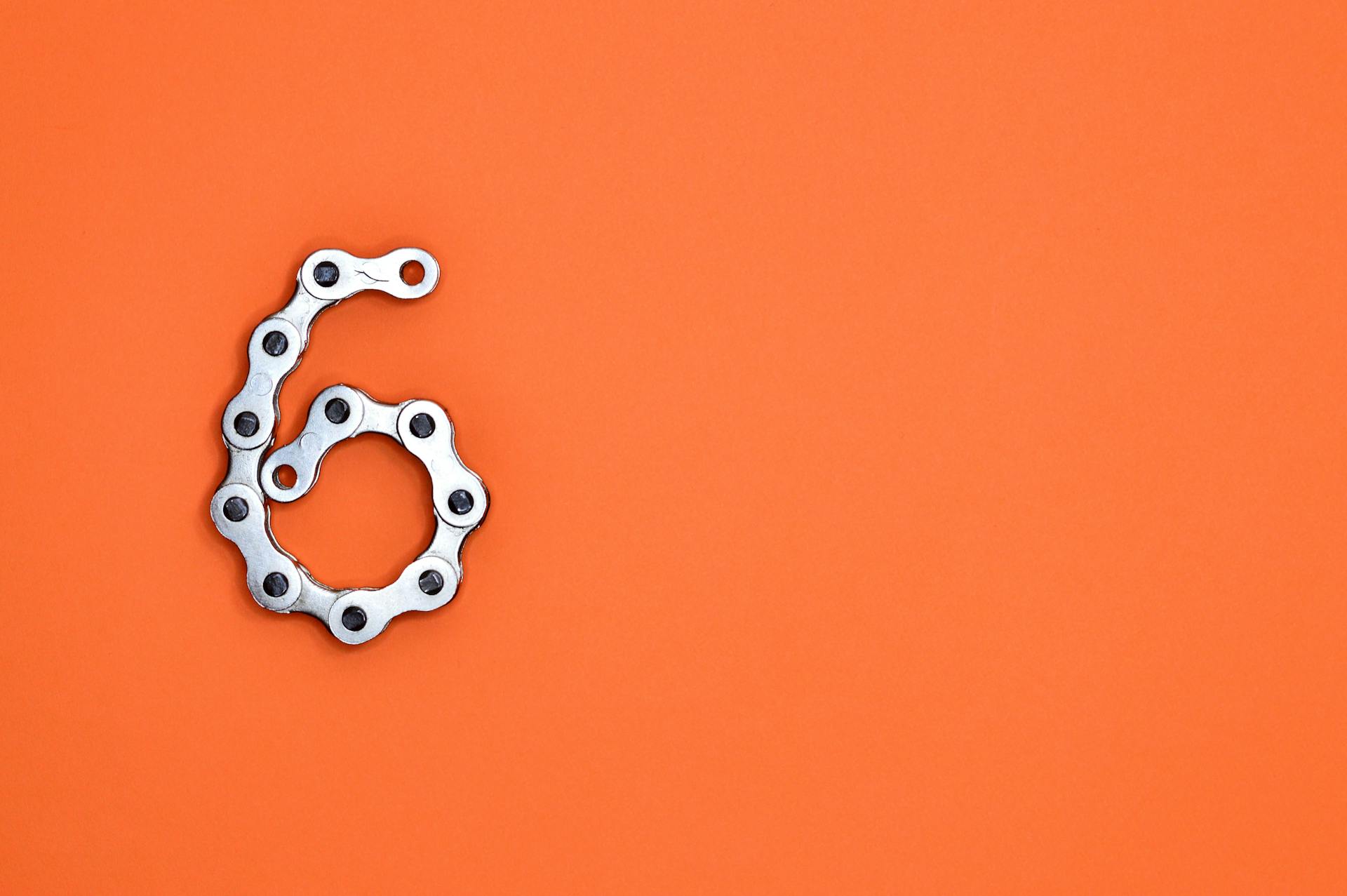 The number six made from a metal bicycle chain on an orange background, representing the six most effective ecommerce personalization tactics covered in the blog.