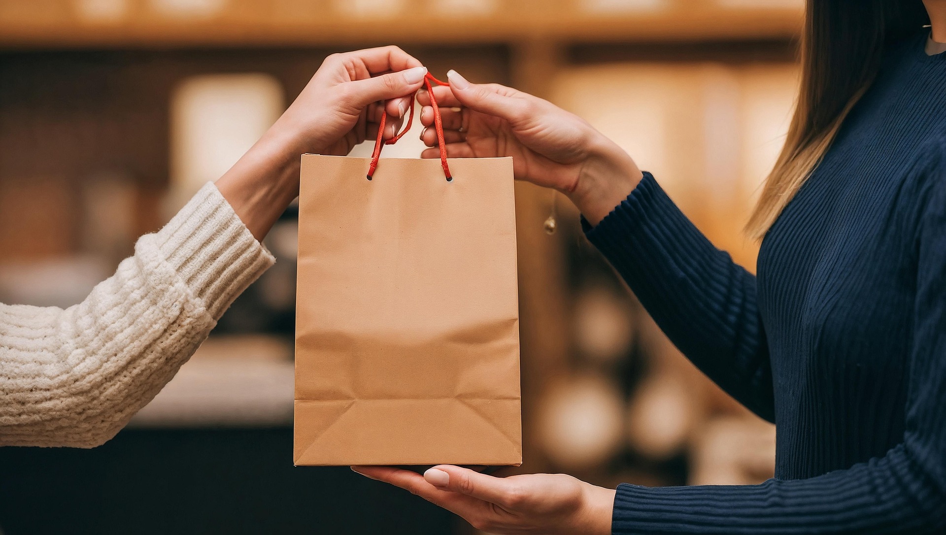 Close-up of two people exchanging a shopping bag, symbolizing a seamless and personalized customer experience—representing the goal of successful ecommerce personalization.