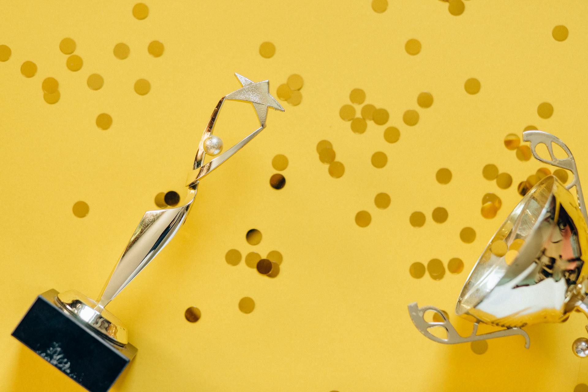 Golden trophies on yellow confetti background—representing high-performing paid ads, top ROI campaigns, and award-worthy digital advertising results.