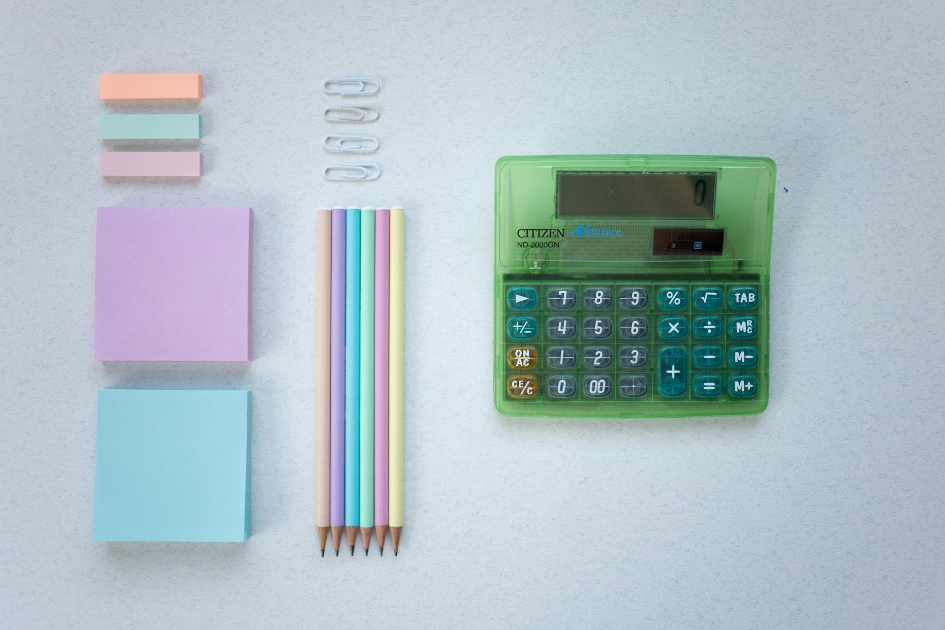 Flat lay of colorful office supplies including sticky notes, pencils, and a calculator—symbolizing PPC budgeting, paid ads campaign planning, and ROI calculations.