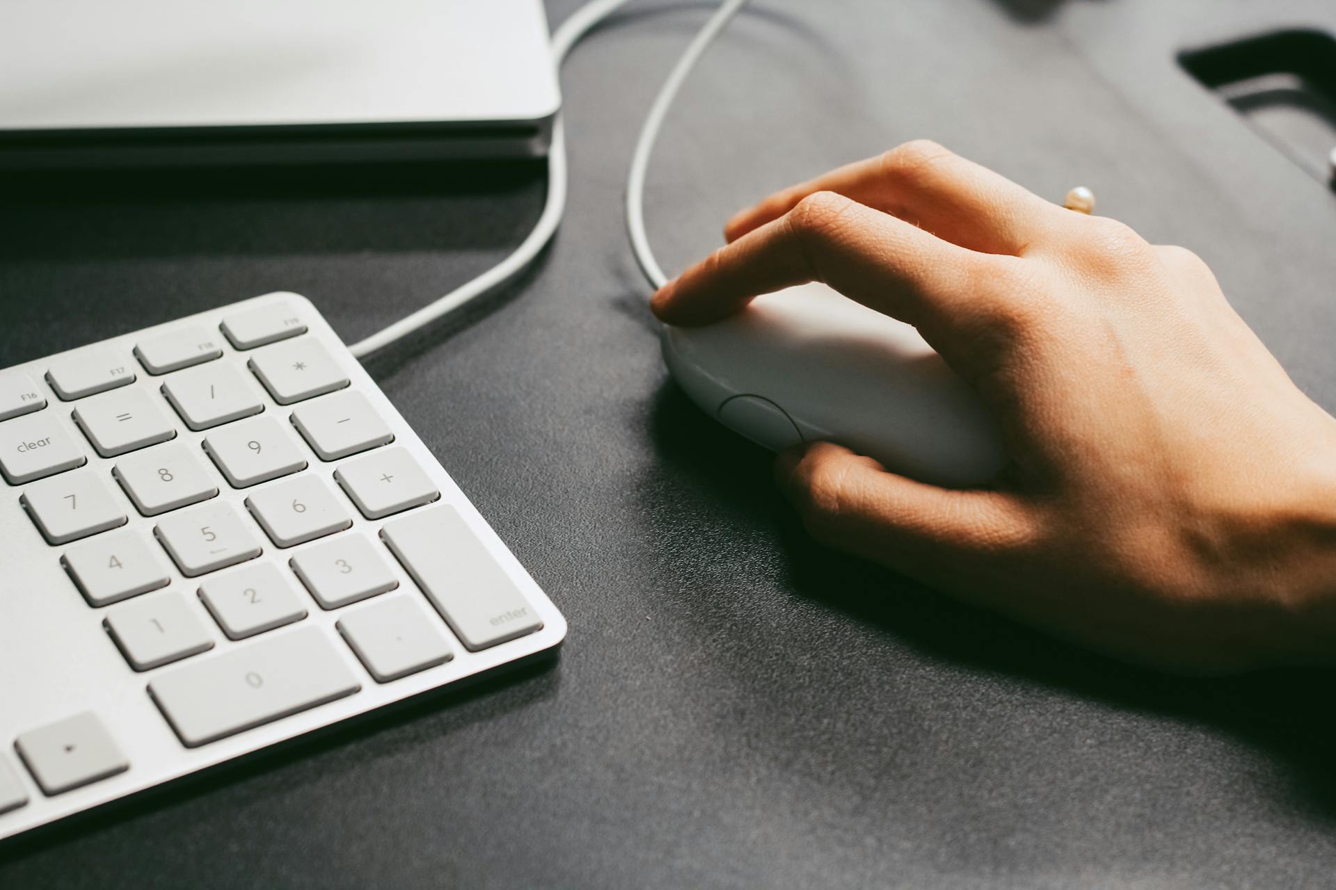 Close-up of a hand clicking a computer mouse next to a numeric keyboard—symbolizing user clicks, PPC ad engagement, and clickthrough rate in paid advertising campaigns.