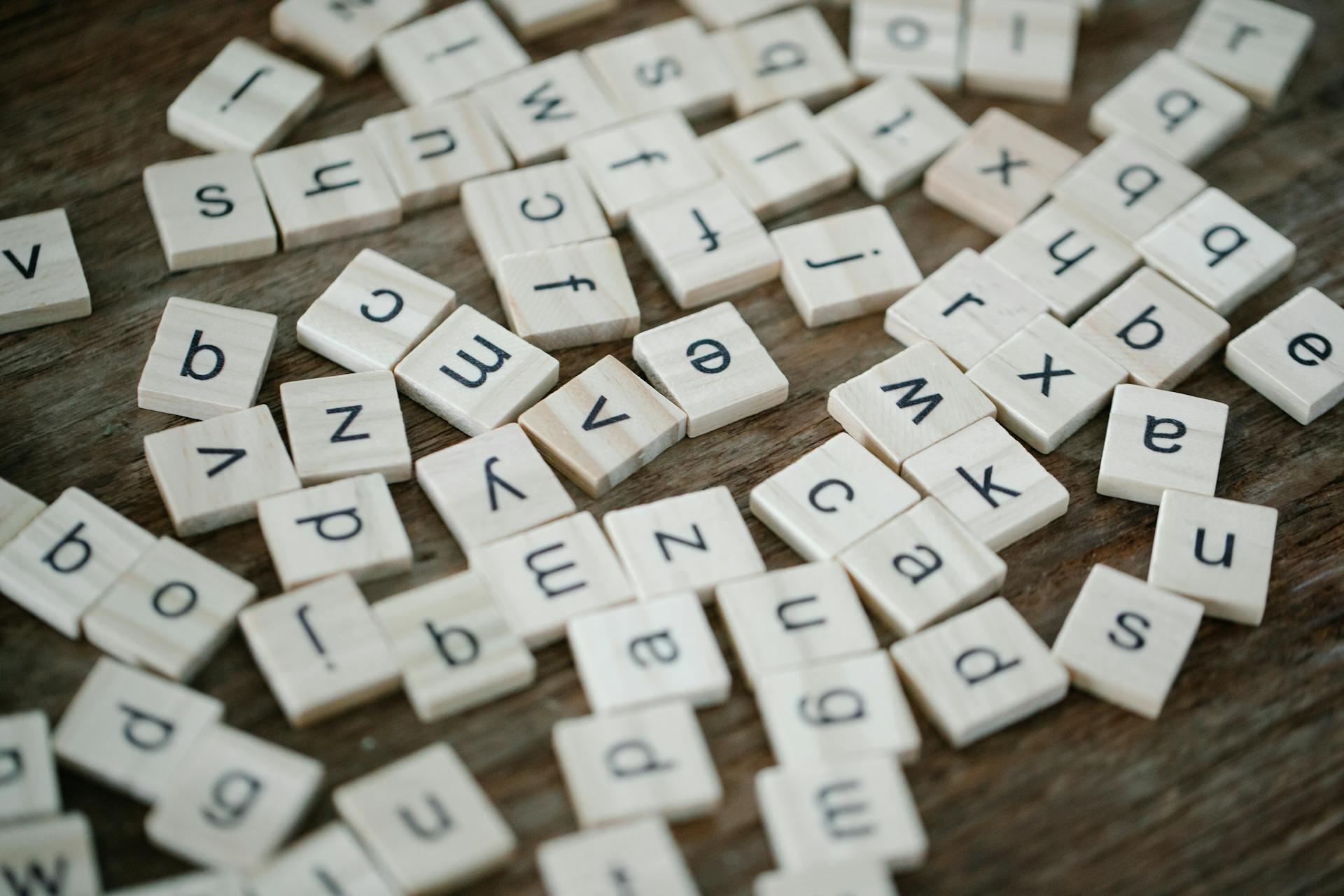 Scattered wooden letter tiles on a table, symbolizing the confusion around digital marketing acronyms like AEO vs GEO.