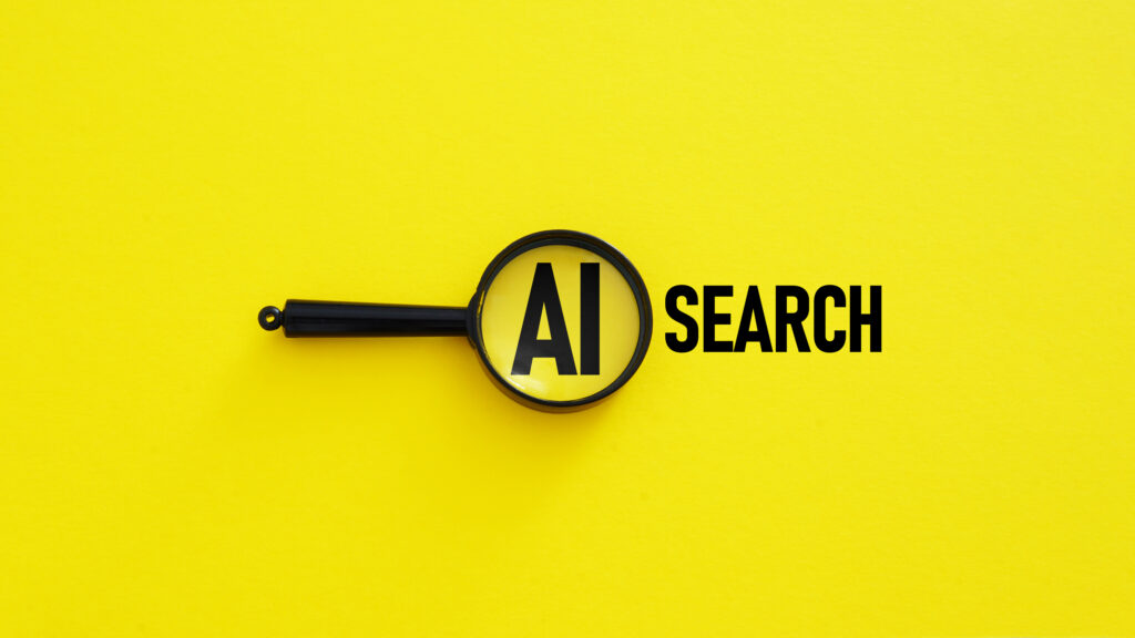 Magnifying glass highlighting the words ‘AI Search’ on a bright yellow background – concept image for AEO vs GEO in modern search optimization.