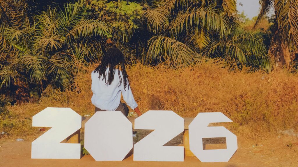 Person sitting beside large white “2026” numbers outdoors, symbolizing a look ahead into the future of ecommerce trends 2026 against a natural background.
