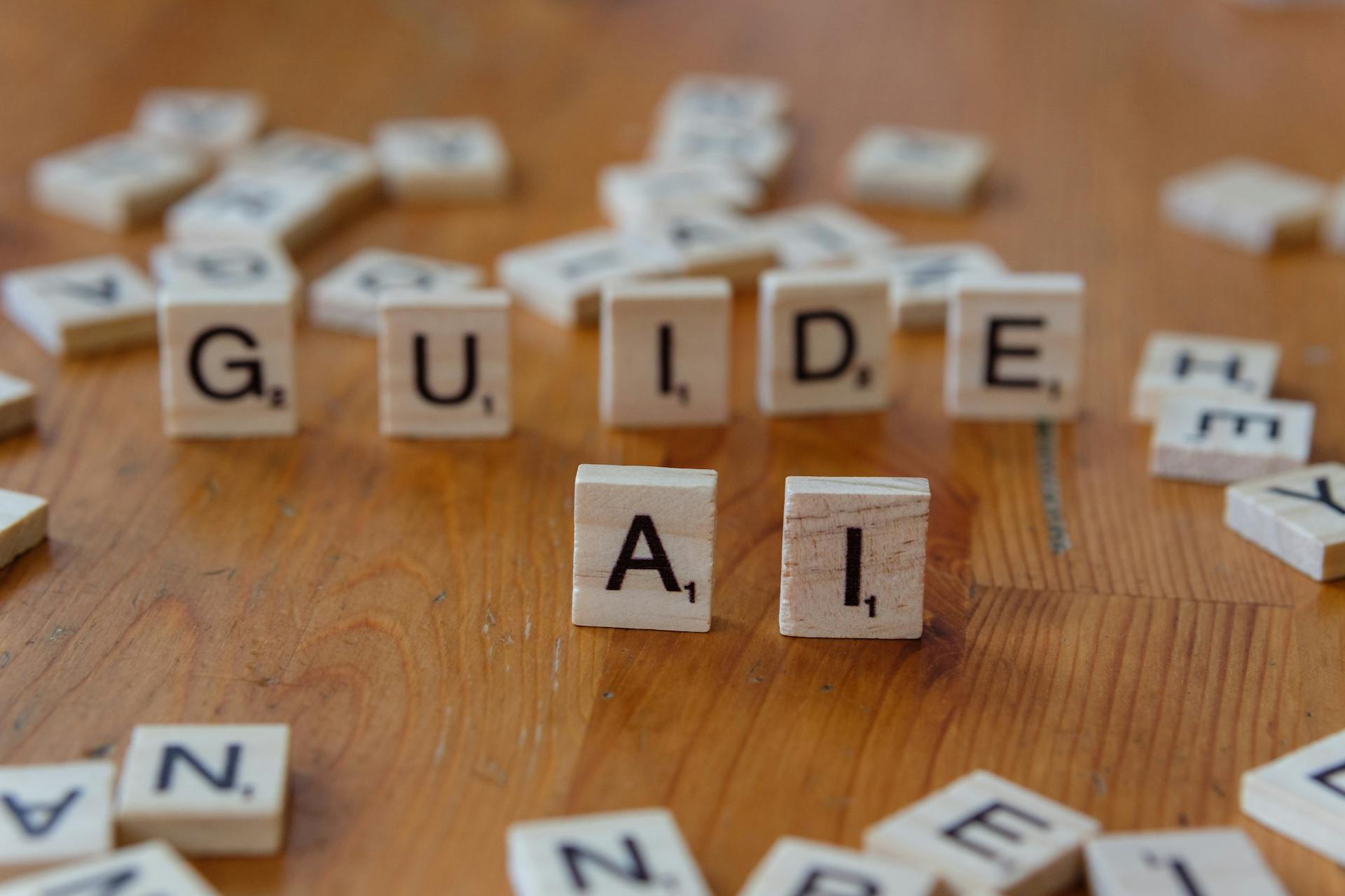 Wooden letter tiles spelling out ‘GUIDE’ and ‘AI’ on a wooden surface, representing an educational guide on AEO and GEO in the context of AI-driven search.