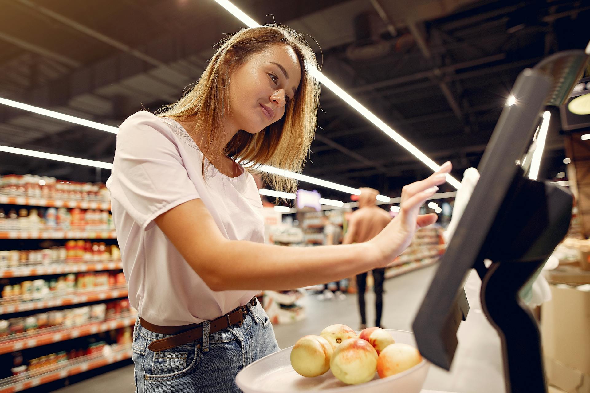 Customer using self-checkout kiosk in grocery store, illustrating seamless checkout process and retail conversion optimization experience.
