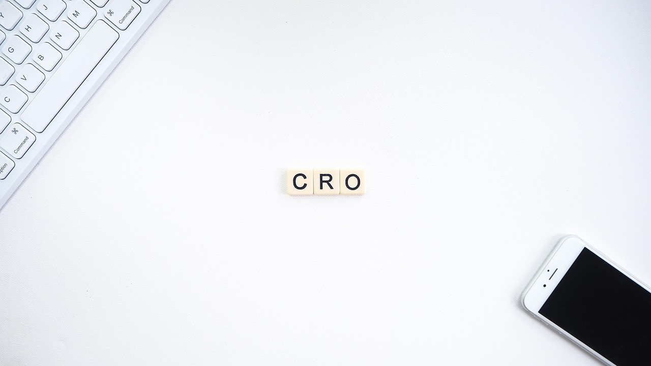 CRO letters on a white background with a smartphone and keyboard, symbolizing Ecommerce Conversion Optimization strategies for digital growth.