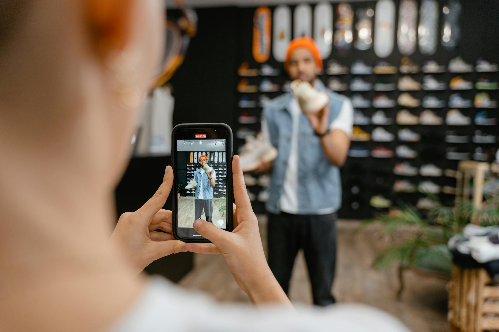 Person filming sneakers in a retail store, representing product content used in product detail pages (PDPs) for AI shopping and ecommerce product discovery.