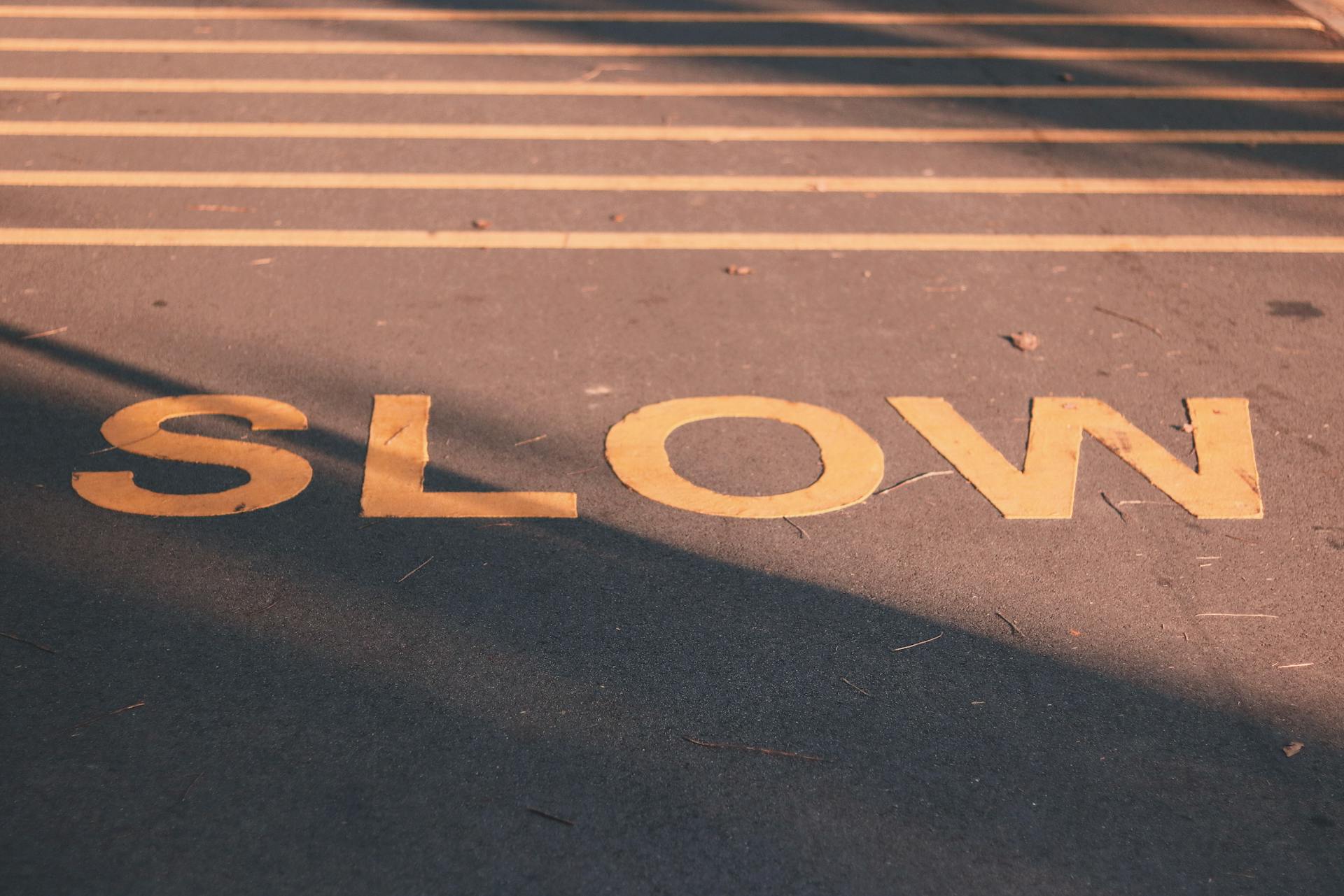 “Slow” written on a road surface, symbolizing slow website performance affecting ecommerce marketing results, conversion rates, and online store growth.