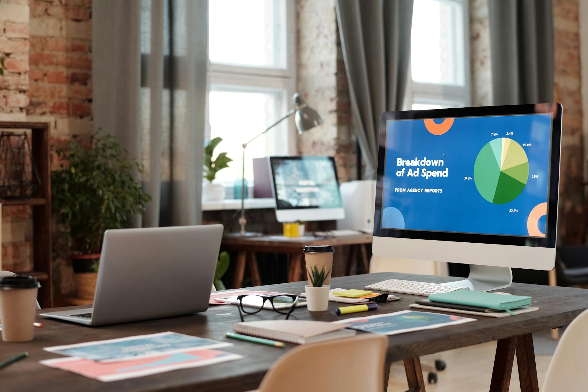 Office workspace with computer screen displaying ad spend analytics and charts, illustrating ecommerce marketing performance, paid advertising strategy, and digital marketing analytics.