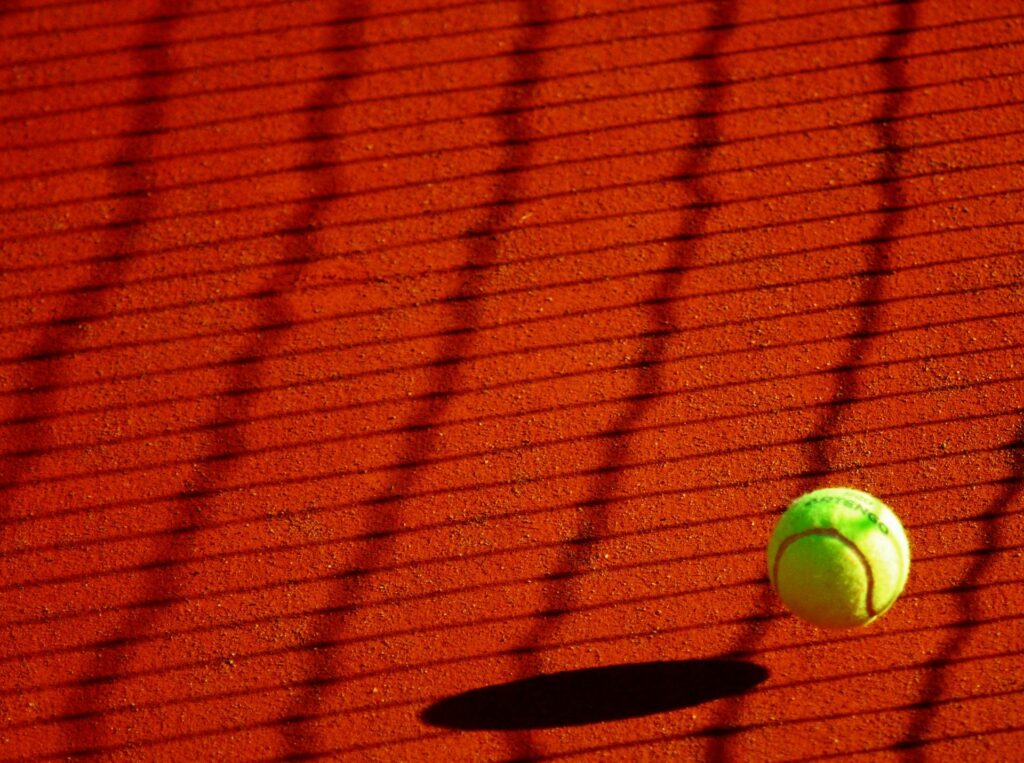 Tennis ball mid-bounce on red clay, metaphor for ecommerce bounce rate and rapid user exits from landing pages with poor UX or slow page load speed