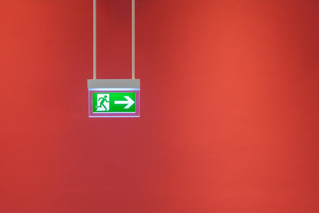Exit sign on red wall symbolizing exit rate vs bounce rate in ecommerce analytics