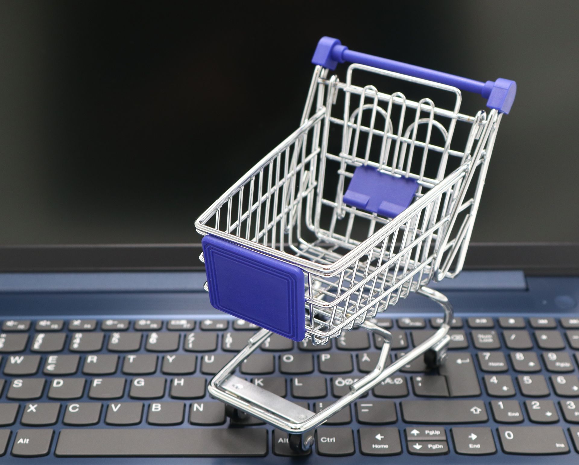 Shopping cart on a laptop keyboard representing a Shopify store, ecommerce performance optimization, and the importance of reducing render-blocking resources to create a faster shopping experience and improve conversions.