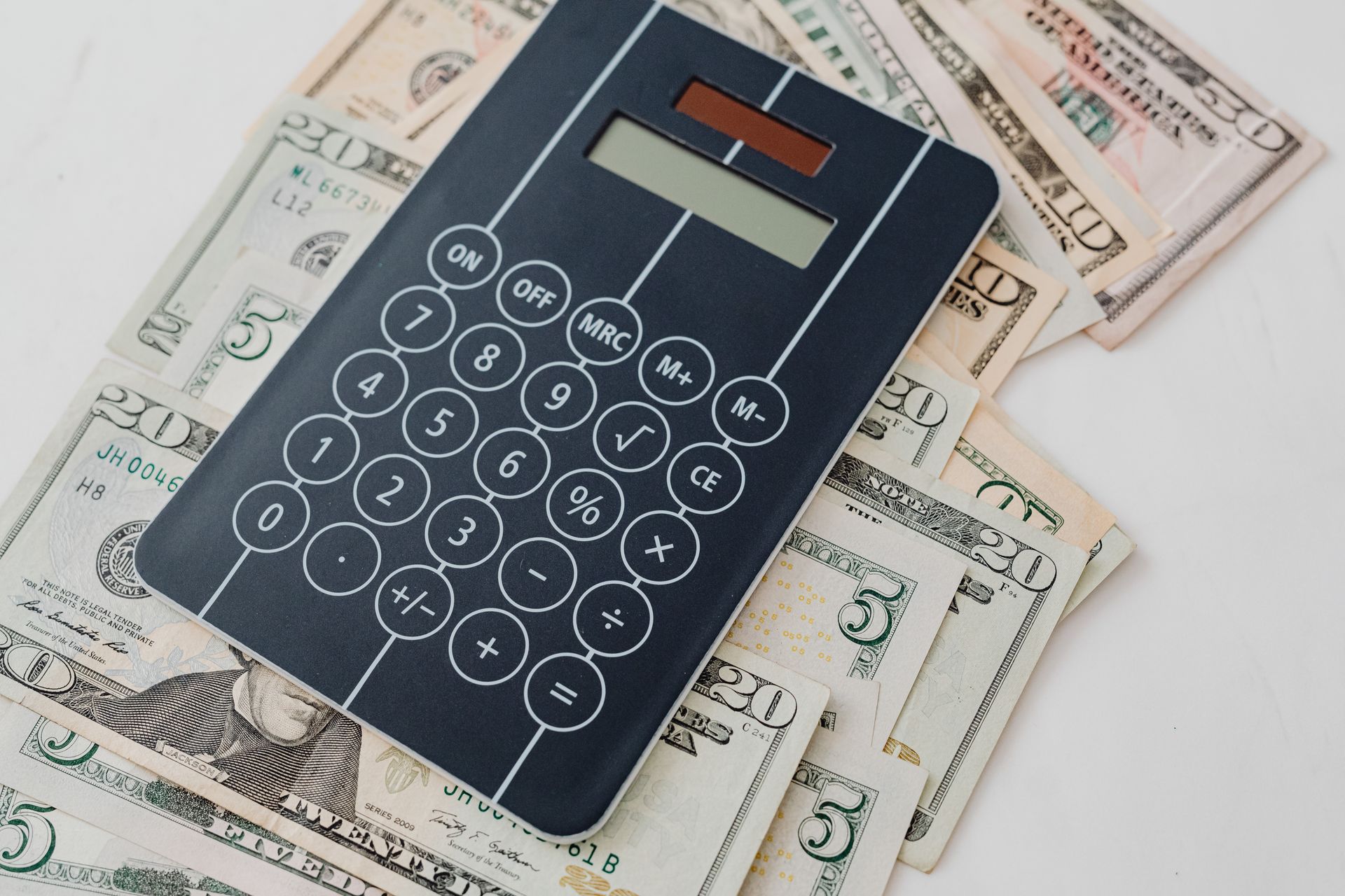 Calculator placed on top of dollar bills, representing the hidden financial cost of ecommerce tools and third-party software. Visual illustration of how Shopify apps slow down store performance, increase website speed challenges, and create ongoing performance costs for the average Shopify store.